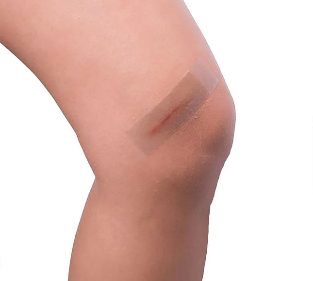 Transparent adhesive bandage on knee wound, first aid for minor injuries